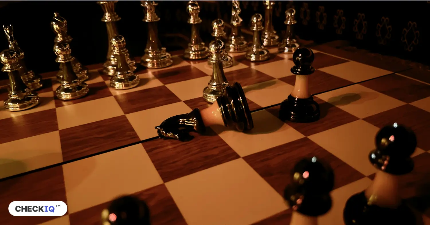 A chessboard featuring golden and darker pieces, with one of the darker pieces fallen over